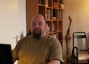 Ein Mann sitzt am Computer vor Bücherregalen in einem schönen Homeoffice
