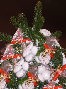Weiße Schale mit Tannenzweigen und kleinen Geschenktütchen