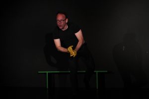 Schauspielunterricht im TheaterLabor TraumGesicht: Peter in schrwarzer Übungskleidung auf der Probebühne übt starke Hand- und Körpergebärden. Er trägt goldgelbe Glitzerhanschuhe.