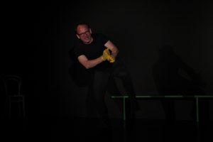 Schauspielunterricht im TheaterLabor TraumGesicht: Peter in schrwarzer Übungskleidung auf der Probebühne übt starke Hand- und Körpergebärden. Er trägt goldgelbe Glitzerhanschuhe.