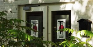 Eingang des Pavillons mit den beiden Glastüren. Dort aufgeklebt das Logo des TheaterLabor TraumGesicht. iel Raum für Ehrenamt.