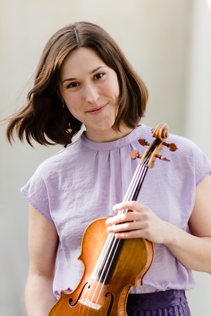 Eine junge Frau hält lächelnd eine Geige in Händen