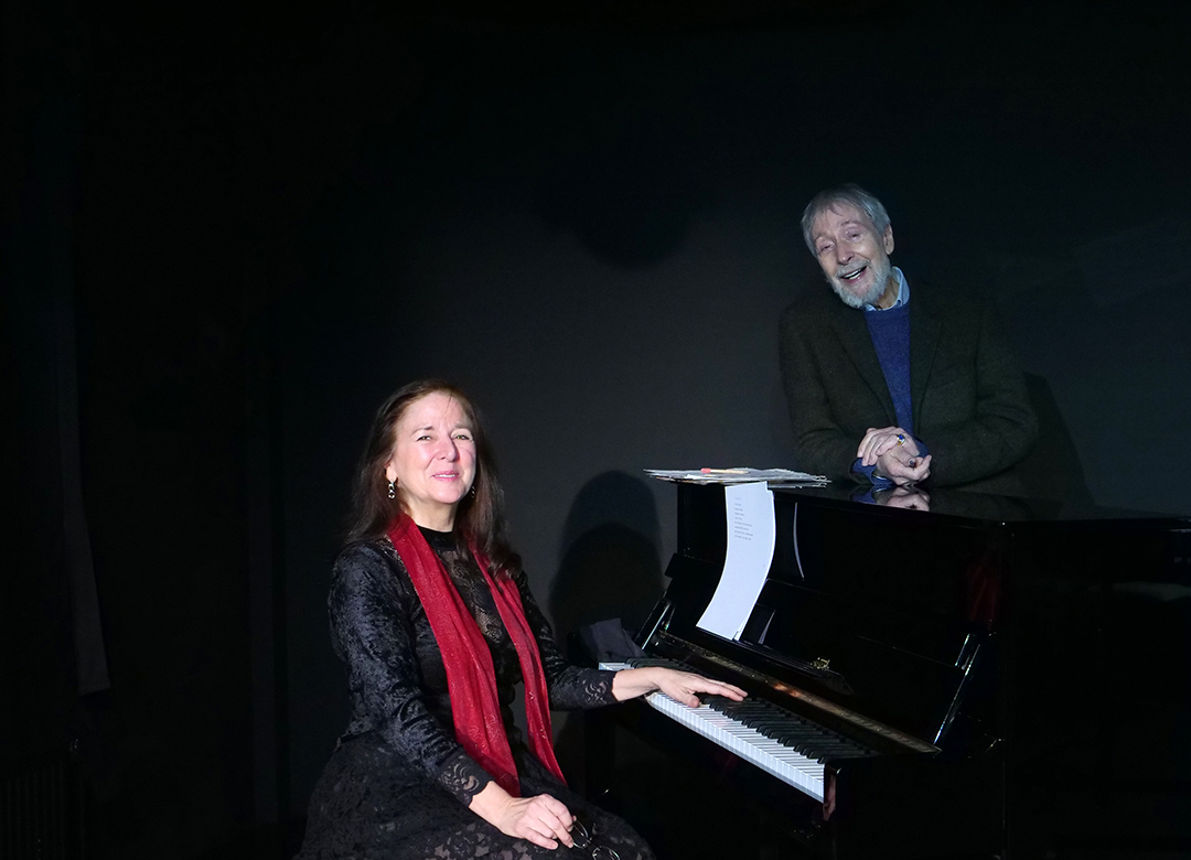 Sybille und Wolfgang_web Szene aus der Tor und der Tod. Eine Schauspielerin, die Mutter, steht mit glitzernder Jacke in der Mitte der Bühne. Sie hat einen starken gesichtsausdruck.