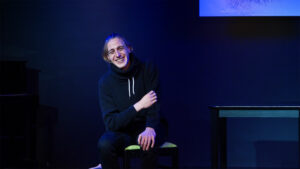 Ein Schauspieler sitzt lachen auf der Bühnen