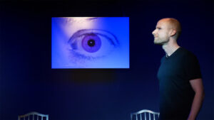 Ein Schauspieler steht im Profil auf der Bühne mit Blick nach links