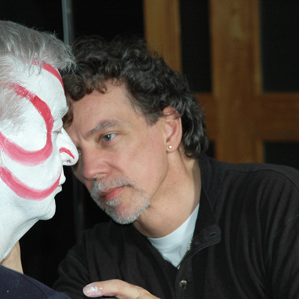 Gianni Sarto schminkt einem Darsteller eine weiße, asiatische Maske. Nahaufnahme beim Schminken eines Darstellers mit weißer Schminkmaske als Ausdrucksmittel im Slow Acting Training.